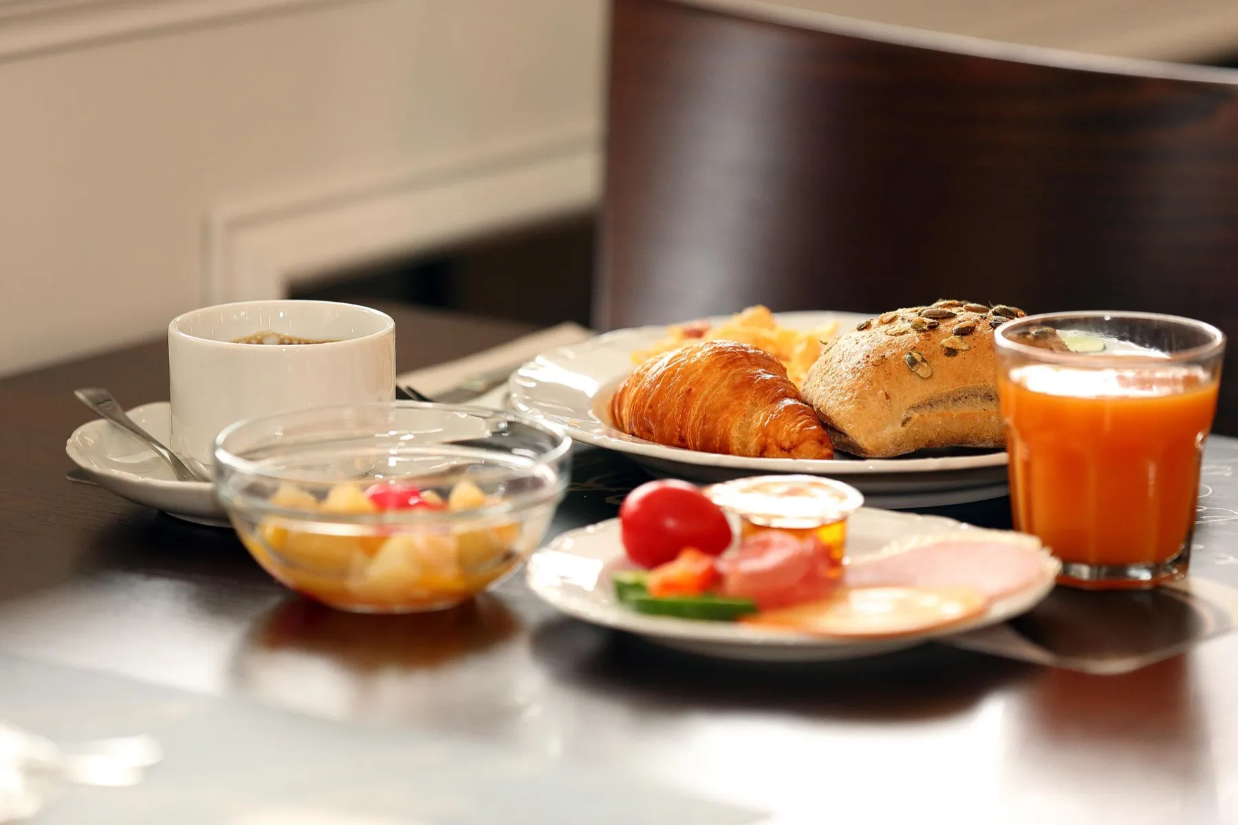 Gedeckter Frühstückstisch mit Croissant, Obst und Orangensaft im Arena Hotel