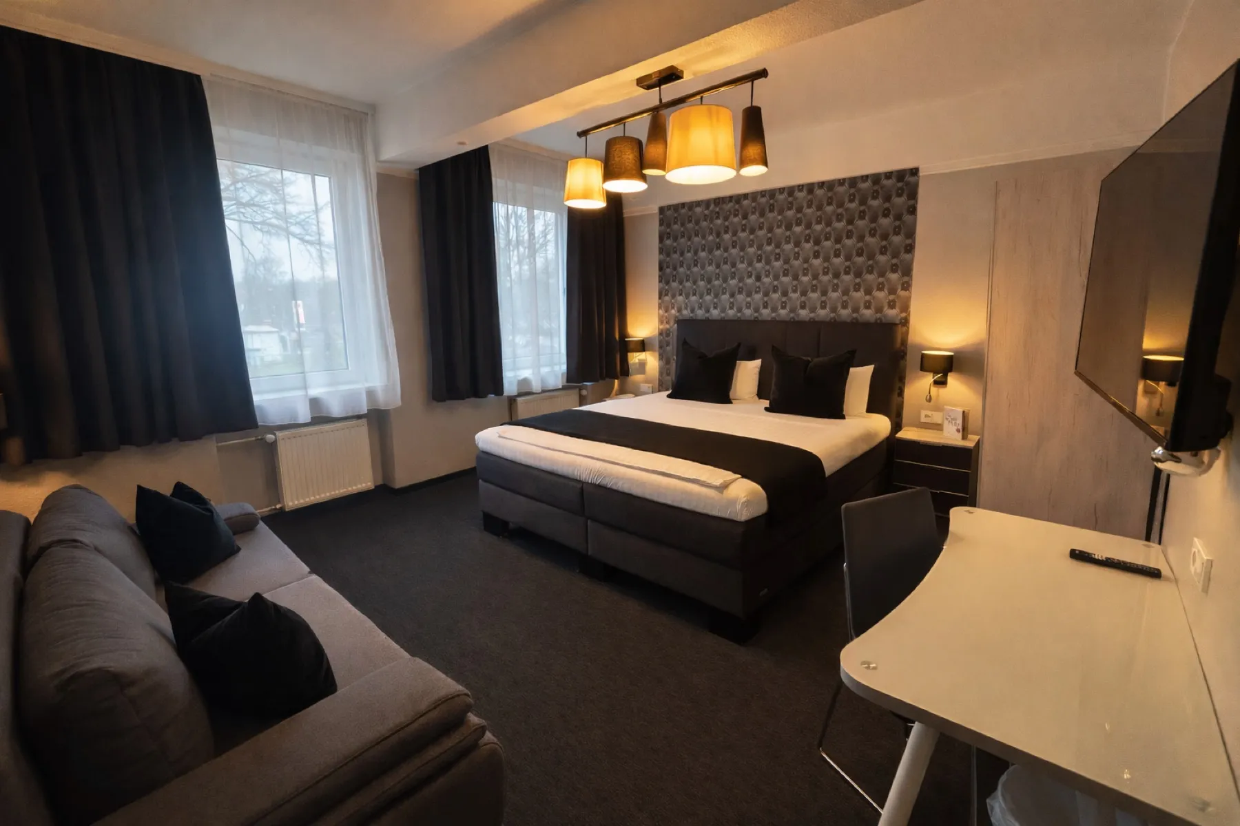 Doppelzimmer mit großem Bett, Sofa und Schreibtisch im Arena Hotel